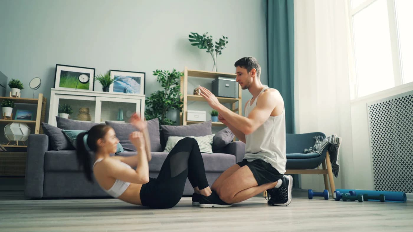 Trainer counting sit-ups for a client during a home visit