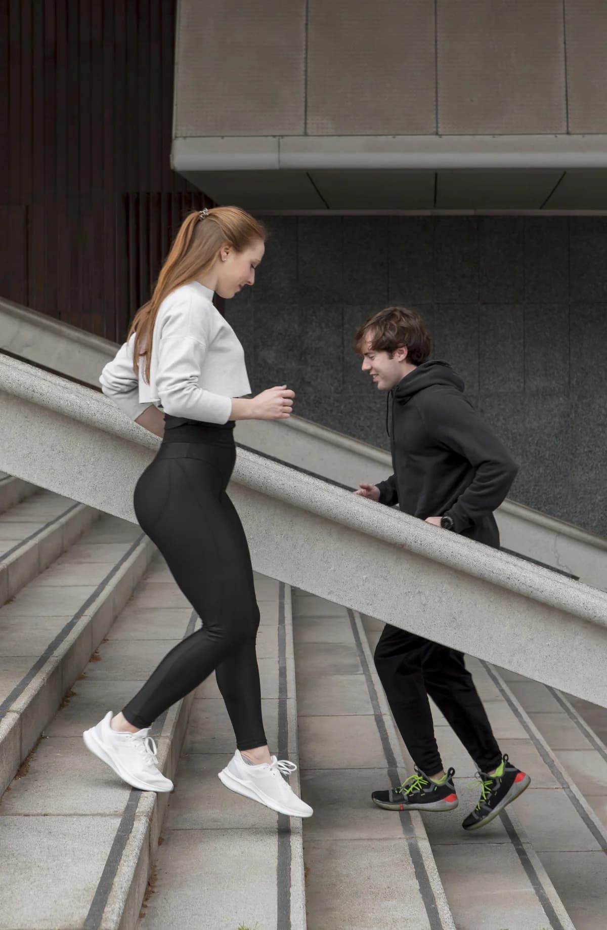 Trainer running stair intervals outdoors alongside a client