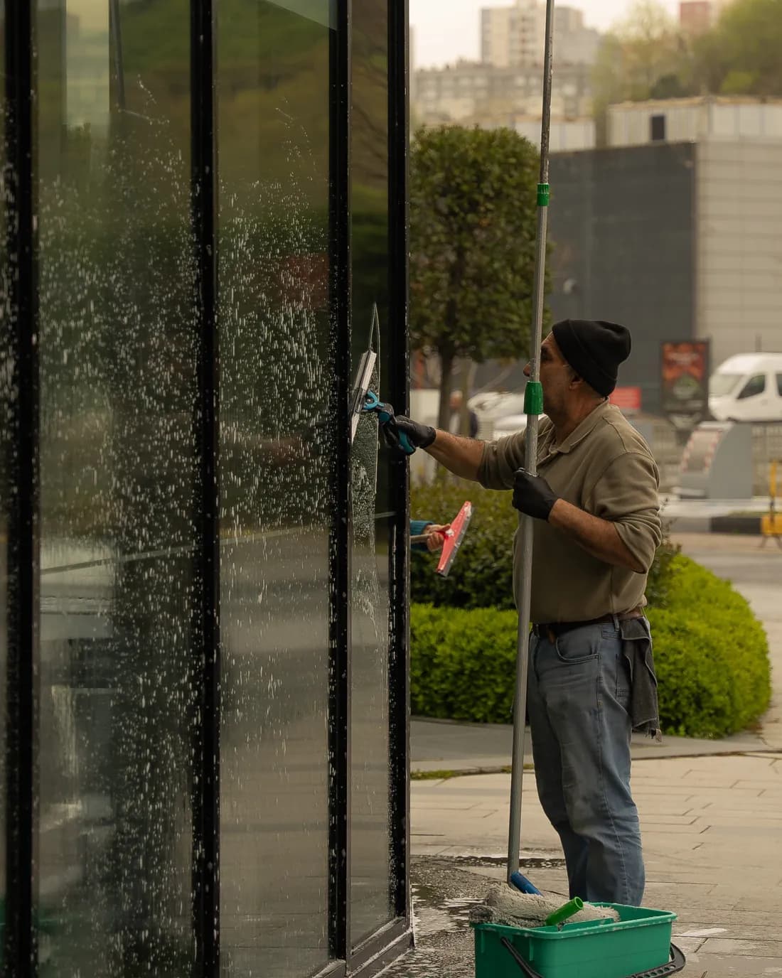 Cleaner washing an office window with a squeegee