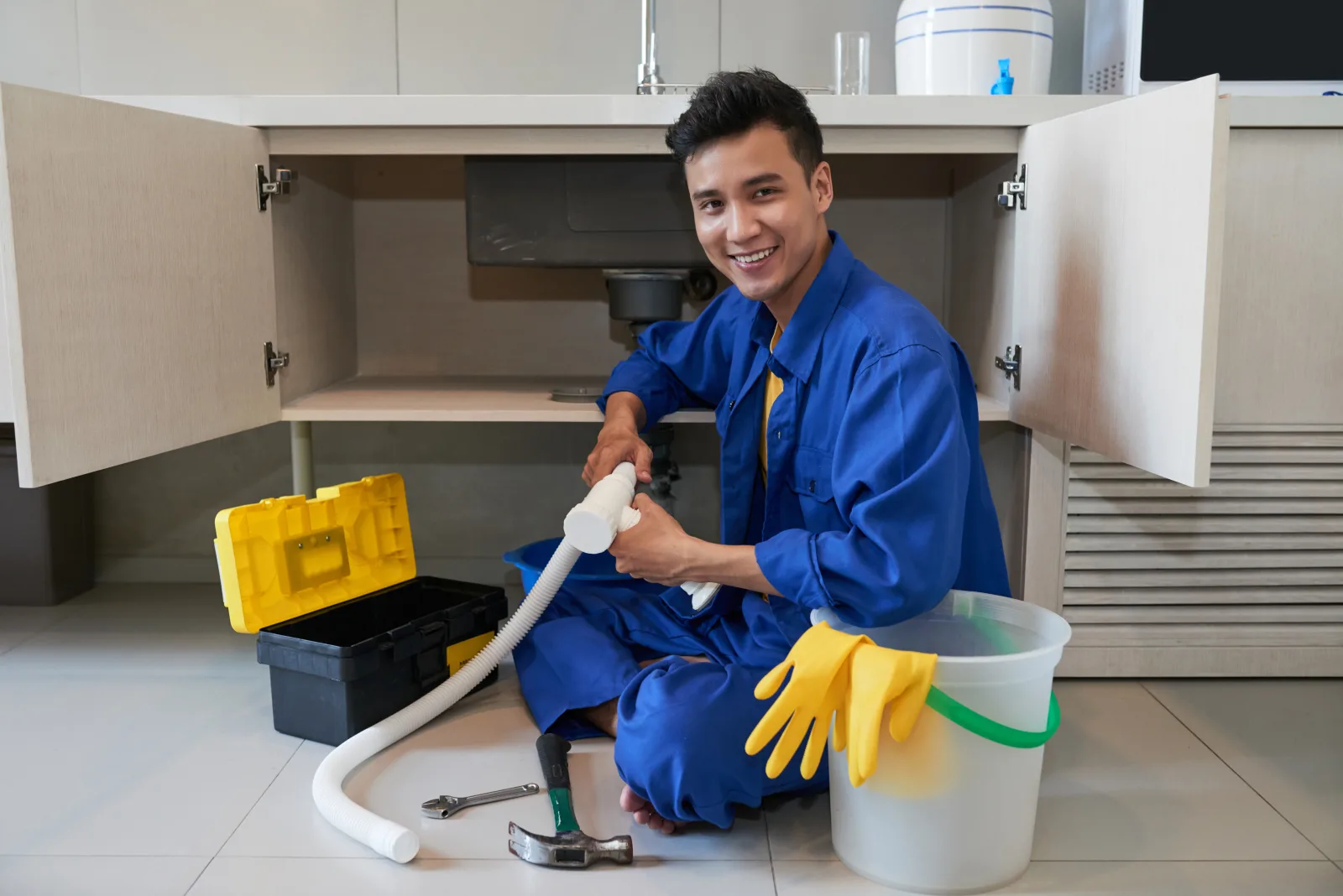 Plumber fitting a pipe under a kitchen sink